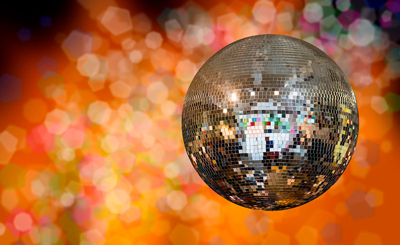 Metallinen discopallo kimaltelee oranssinsävyisellä taustalla.