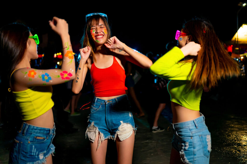 Värikkäisiin vaatteisiin pukeutuvat naiset tanssivat illalla ulkona.